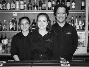 Mari flankert av sine kollegaer i baren. Det beste sjekketrikset er visstnok å jobbe i bar. Mari flankert av sine kollegaer i baren. Det beste sjekketrikset er visstnok å jobbe i bar.