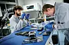 To forskere arbeider med elektronisk utstyr ved en laboratoriebenk.