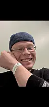 Smilende Rubens med briller og strikkelue, iført sykehusarmbånd.