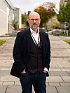 Thomas Østerlie står i mørk jakke pute på Gløshaugen.